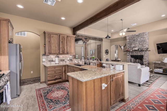 kitchen featuring kitchen peninsula, stainless steel appliances, ceiling fan, sink, and pendant lighting