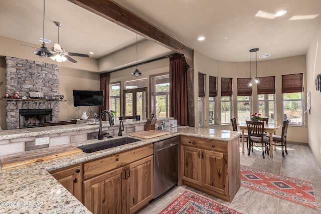 kitchen with a stone fireplace, stainless steel dishwasher, a healthy amount of sunlight, and sink