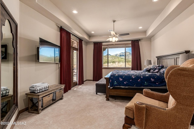 carpeted bedroom with ceiling fan and a raised ceiling