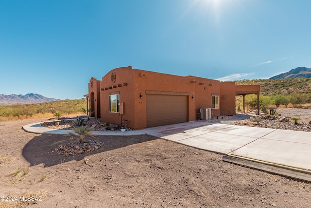 southwest-style home with central air condition unit, a mountain view, and a garage