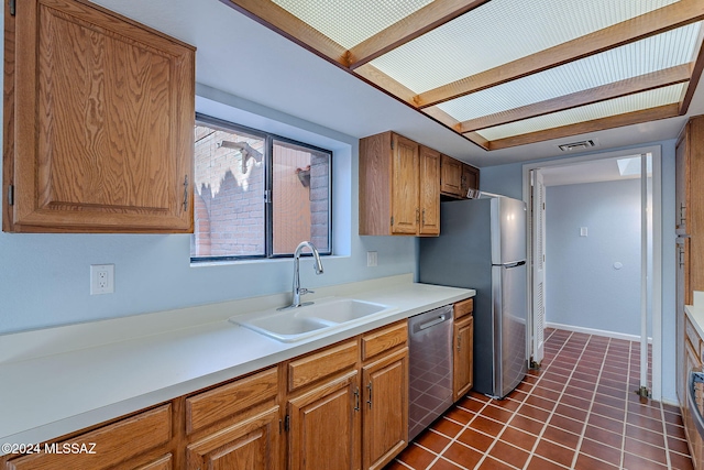 kitchen with sink, dark tile patterned floors, and stainless steel appliances