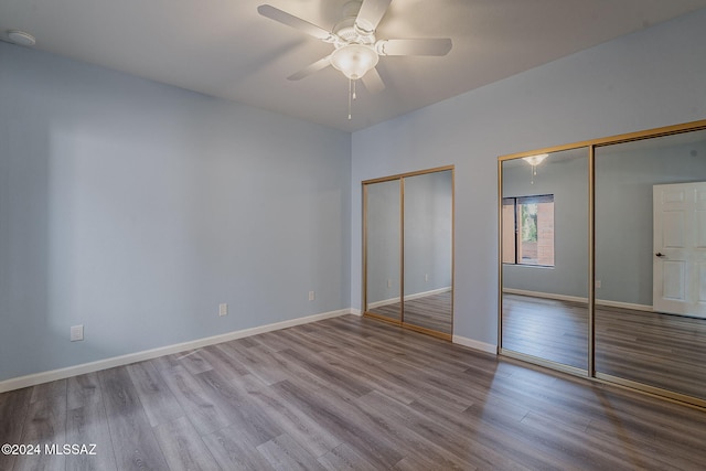 unfurnished bedroom with multiple closets, ceiling fan, and light hardwood / wood-style floors