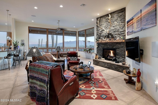 living room featuring ceiling fan, a fireplace, and expansive windows