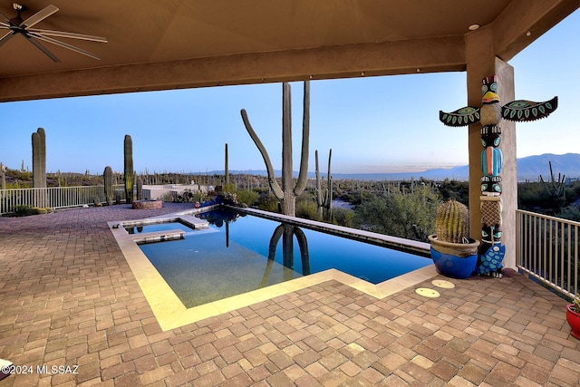 view of pool with an in ground hot tub, a mountain view, and ceiling fan