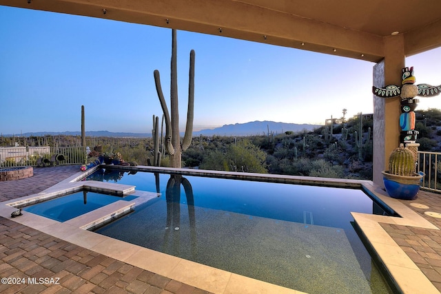 view of swimming pool featuring a mountain view, a patio, and an in ground hot tub