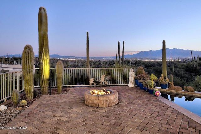 patio terrace at dusk featuring a mountain view and an outdoor fire pit