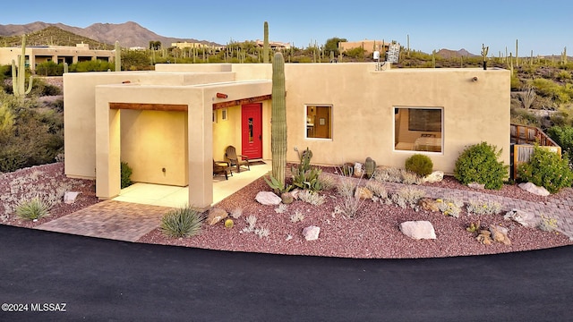 pueblo revival-style home featuring a mountain view and a patio