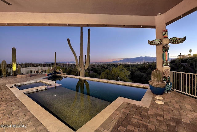 pool at dusk with a mountain view and an in ground hot tub