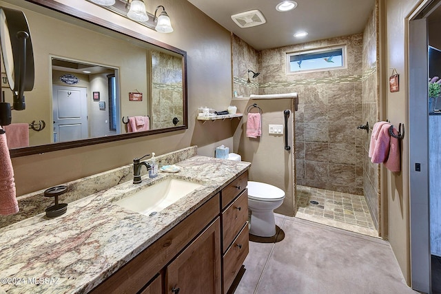 bathroom featuring tile patterned flooring, toilet, vanity, and tiled shower