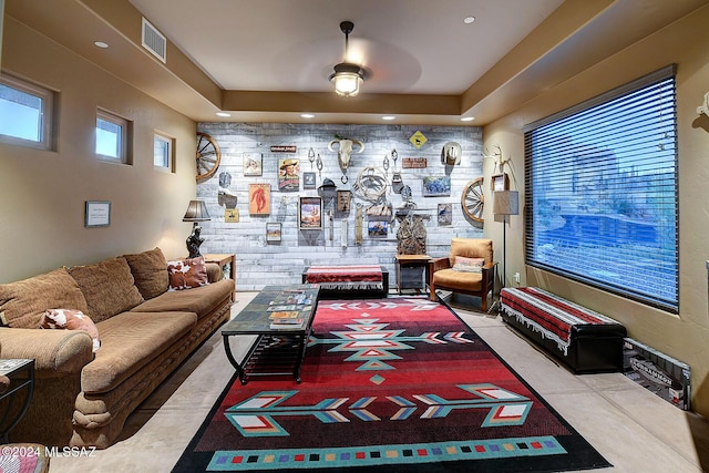 living room featuring ceiling fan and a raised ceiling