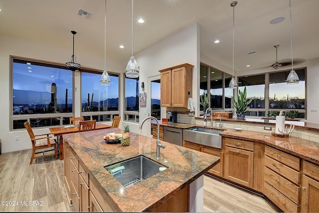 kitchen featuring decorative light fixtures, decorative backsplash, sink, and a large island with sink