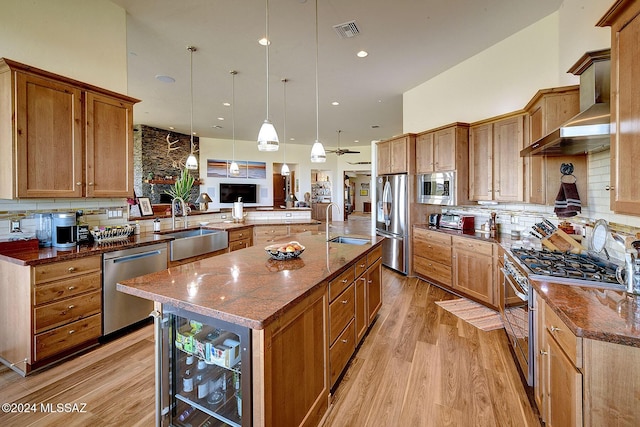 kitchen featuring sink, stainless steel appliances, wine cooler, pendant lighting, and a center island with sink