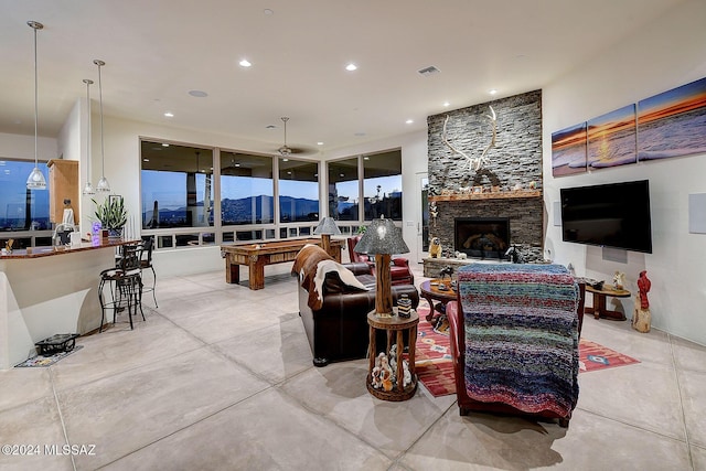 living room featuring ceiling fan, a stone fireplace, and pool table