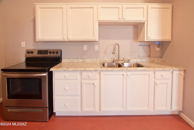 kitchen featuring electric range, light stone counters, white cabinets, and sink