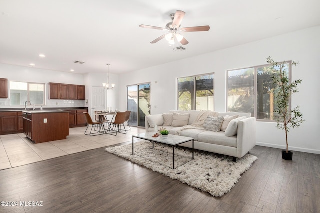 living room with ceiling fan with notable chandelier, light hardwood / wood-style flooring, and sink