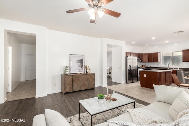 living room featuring light hardwood / wood-style flooring, ceiling fan, and sink