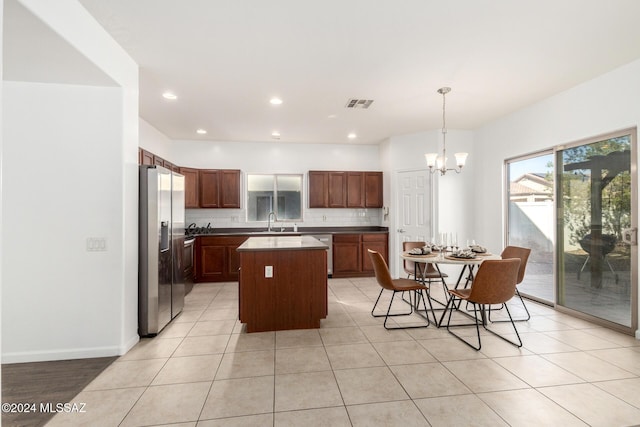 kitchen featuring a center island, sink, appliances with stainless steel finishes, tasteful backsplash, and decorative light fixtures