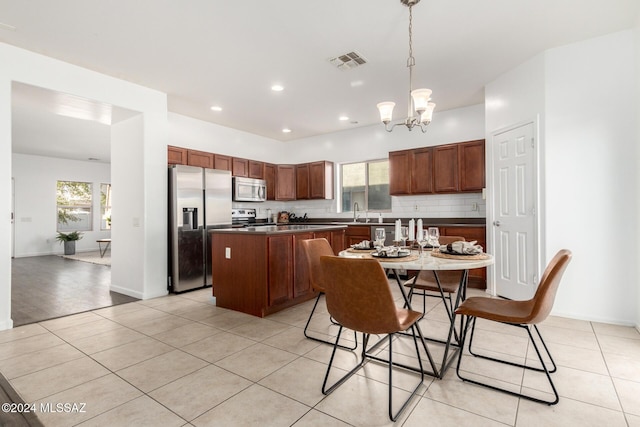 kitchen featuring a center island, hanging light fixtures, decorative backsplash, a notable chandelier, and stainless steel appliances