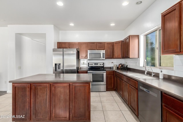 kitchen with light tile patterned floors, stainless steel appliances, a kitchen island, and sink