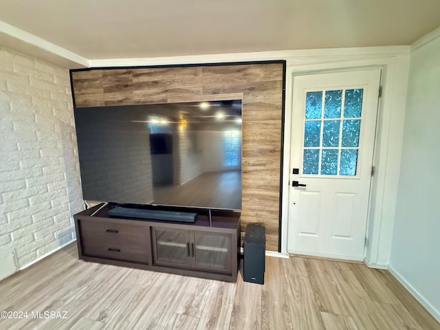 interior space with light hardwood / wood-style floors and brick wall