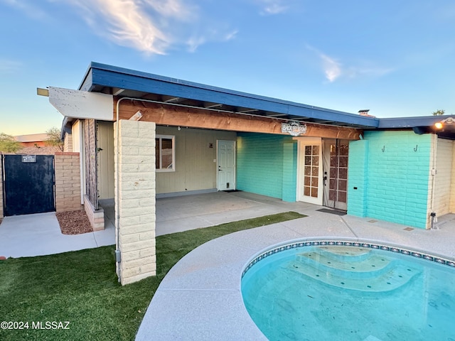 rear view of house with a fenced in pool and a patio