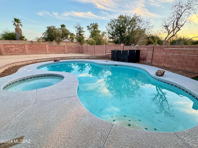 pool at dusk with an in ground hot tub