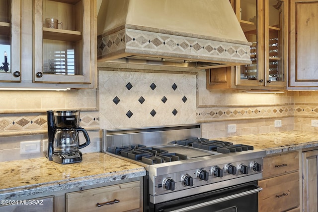 kitchen featuring decorative backsplash, stainless steel range with gas cooktop, and premium range hood