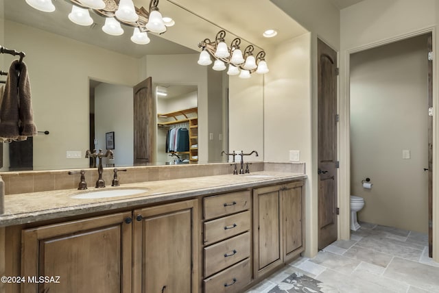 bathroom featuring vanity, toilet, and a notable chandelier