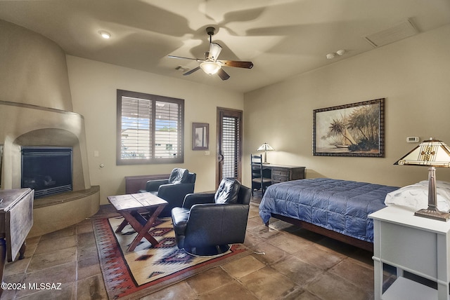 bedroom with ceiling fan and a large fireplace