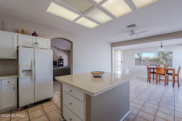 kitchen with white cabinets, ceiling fan, a kitchen island, and white refrigerator with ice dispenser