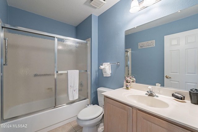 full bathroom featuring tile patterned floors, bath / shower combo with glass door, vanity, a textured ceiling, and toilet