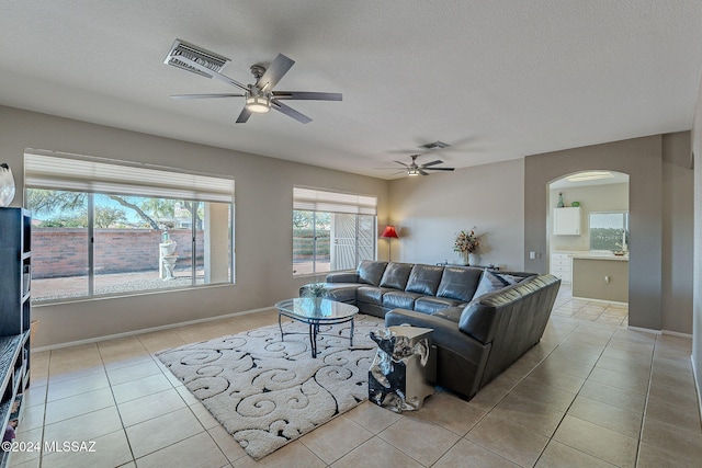 tiled living room with ceiling fan and a textured ceiling