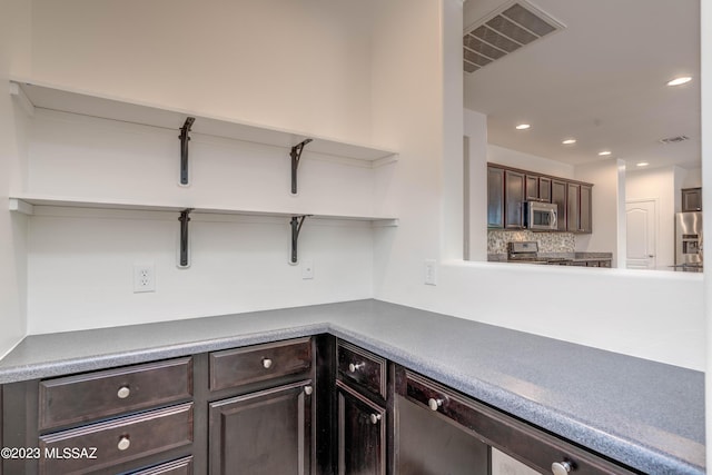 interior space featuring stainless steel appliances, dark brown cabinetry, and backsplash