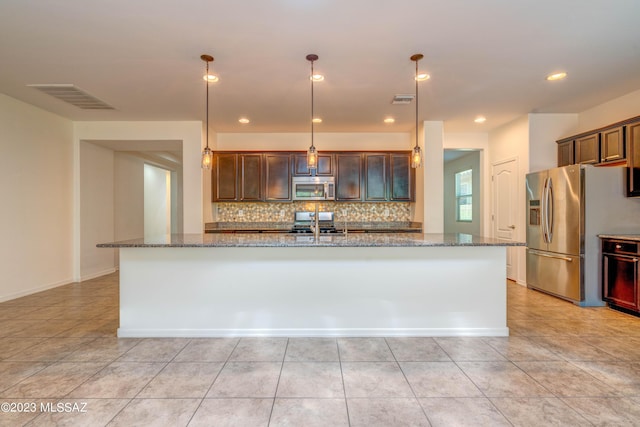 kitchen featuring stainless steel appliances, hanging light fixtures, tasteful backsplash, and light stone counters