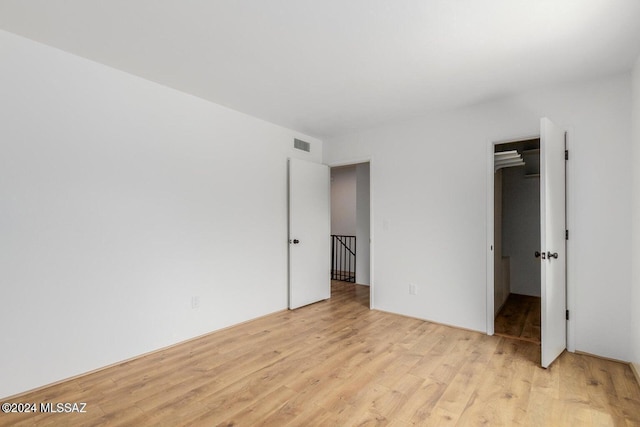 unfurnished bedroom featuring a walk in closet, a closet, and light wood-type flooring