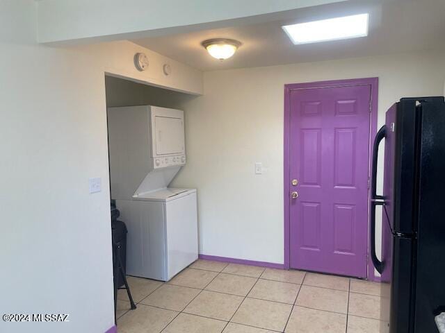 clothes washing area featuring stacked washer / drying machine and light tile patterned floors