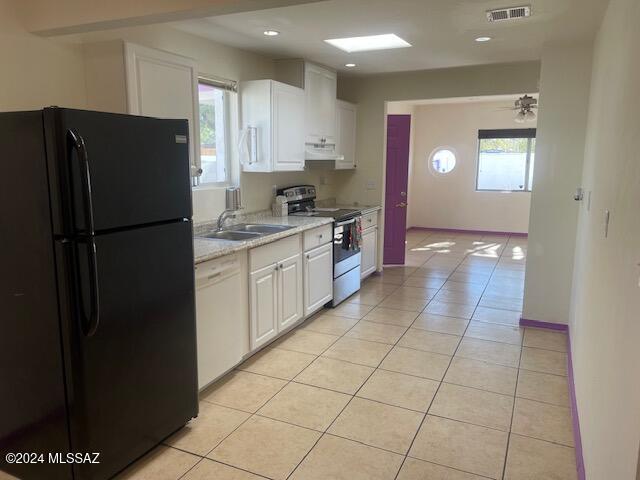 kitchen featuring a wealth of natural light, black fridge, white dishwasher, stainless steel electric stove, and white cabinets