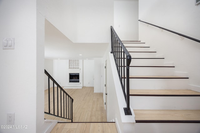 stairs with hardwood / wood-style floors and a brick fireplace