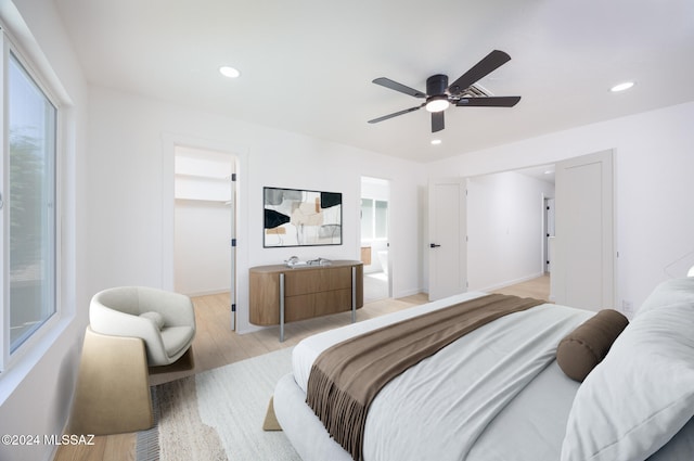 bedroom featuring connected bathroom, a spacious closet, ceiling fan, a closet, and light wood-type flooring