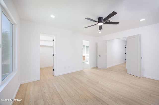 unfurnished bedroom featuring ensuite bath, ceiling fan, a spacious closet, light hardwood / wood-style floors, and a closet