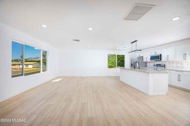 kitchen featuring white cabinets, light wood-type flooring, stainless steel appliances, and a wealth of natural light