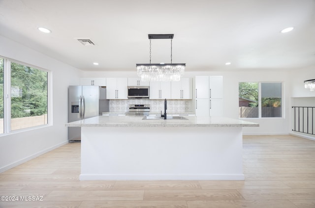 kitchen with white cabinets, plenty of natural light, an island with sink, and appliances with stainless steel finishes