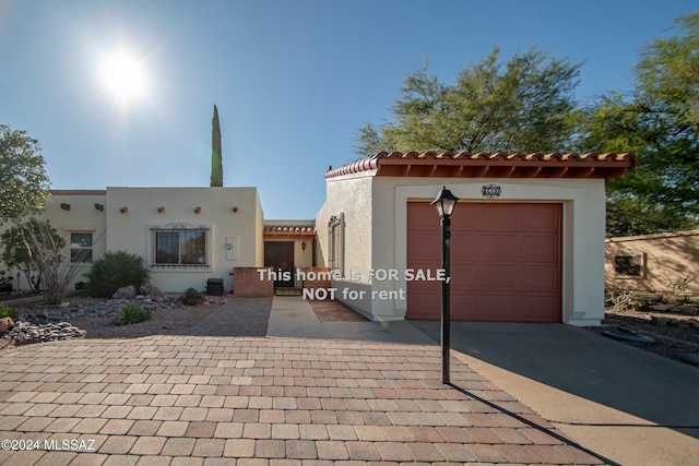 view of front of property with an attached garage, a tile roof, decorative driveway, and stucco siding