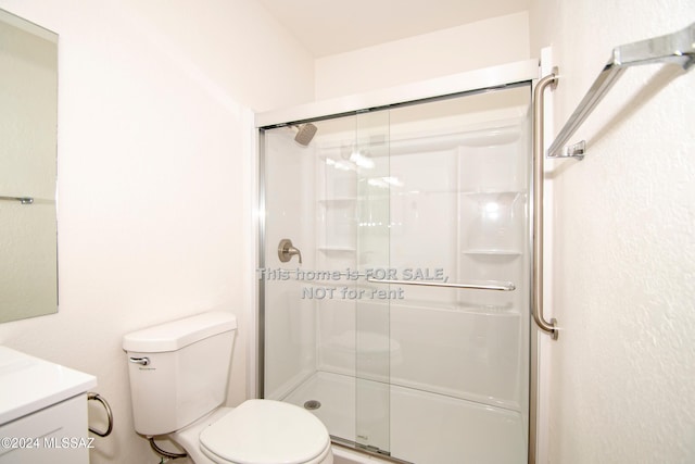 bathroom with a stall shower, vanity, and toilet