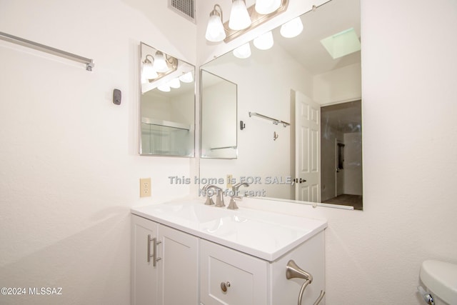 bathroom featuring toilet, vanity, and visible vents