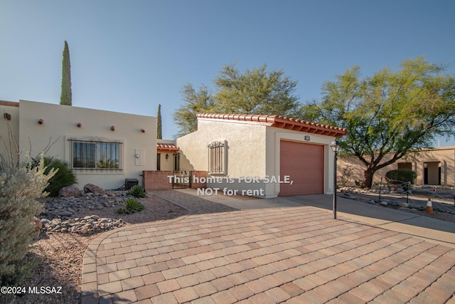 view of front of property with a garage, decorative driveway, a tiled roof, and stucco siding