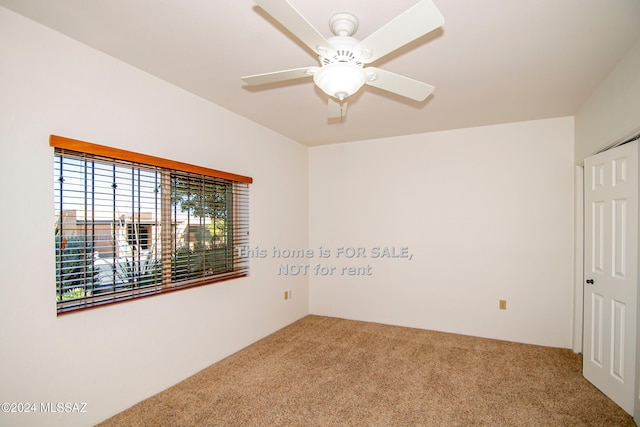 carpeted spare room with a ceiling fan