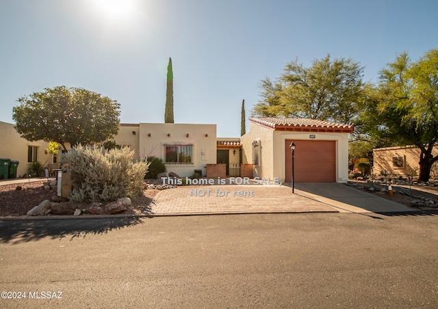 view of front of property with a tile roof, driveway, an attached garage, and stucco siding