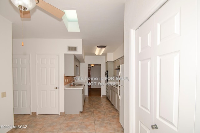 kitchen featuring light tile patterned floors, a sink, visible vents, light countertops, and gray cabinets