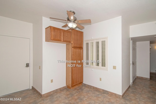 unfurnished bedroom featuring light tile patterned floors, a ceiling fan, and baseboards